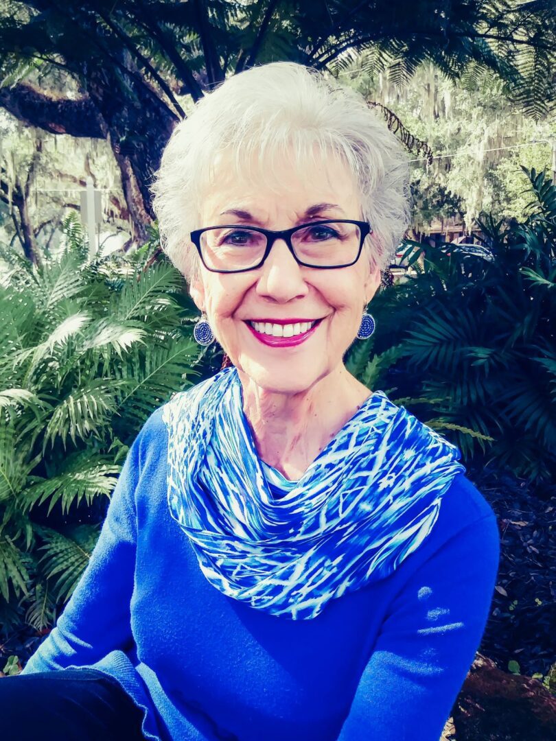 An older woman wearing glasses and a blue sweater.