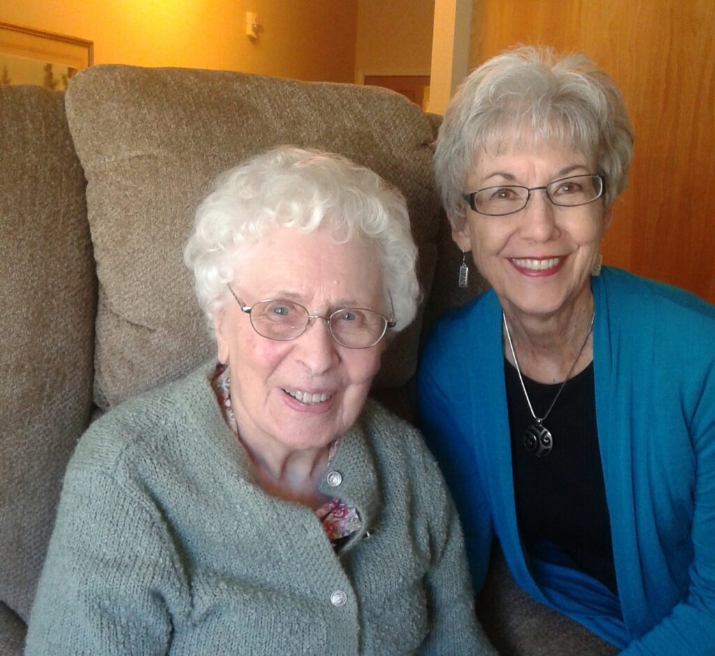 Two older women sitting on a couch.