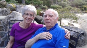 An older couple posing for a photo in a park.